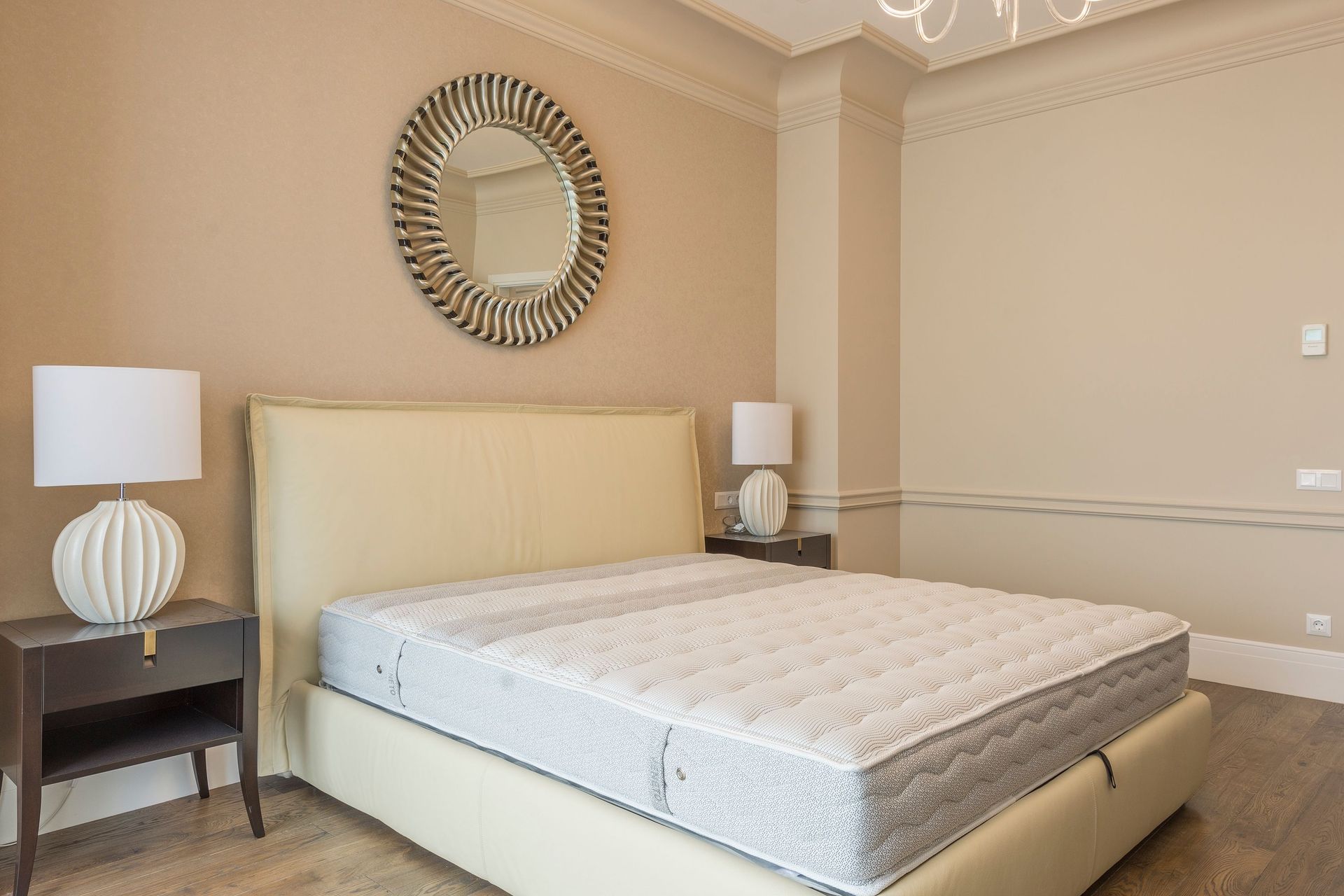 Spacious bedroom featuring modern decor, elegant lighting, and a plush bed with neutral tones.